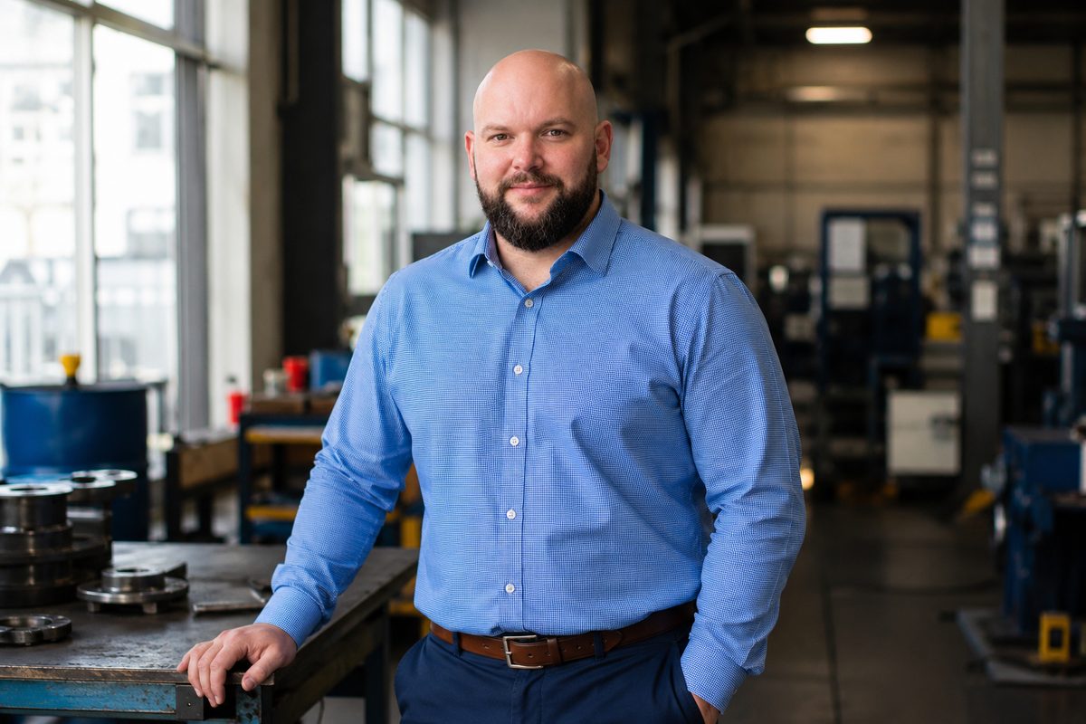 Travis Olson, principal of Headland Safety, standing at a workbench on a machine shop floor.